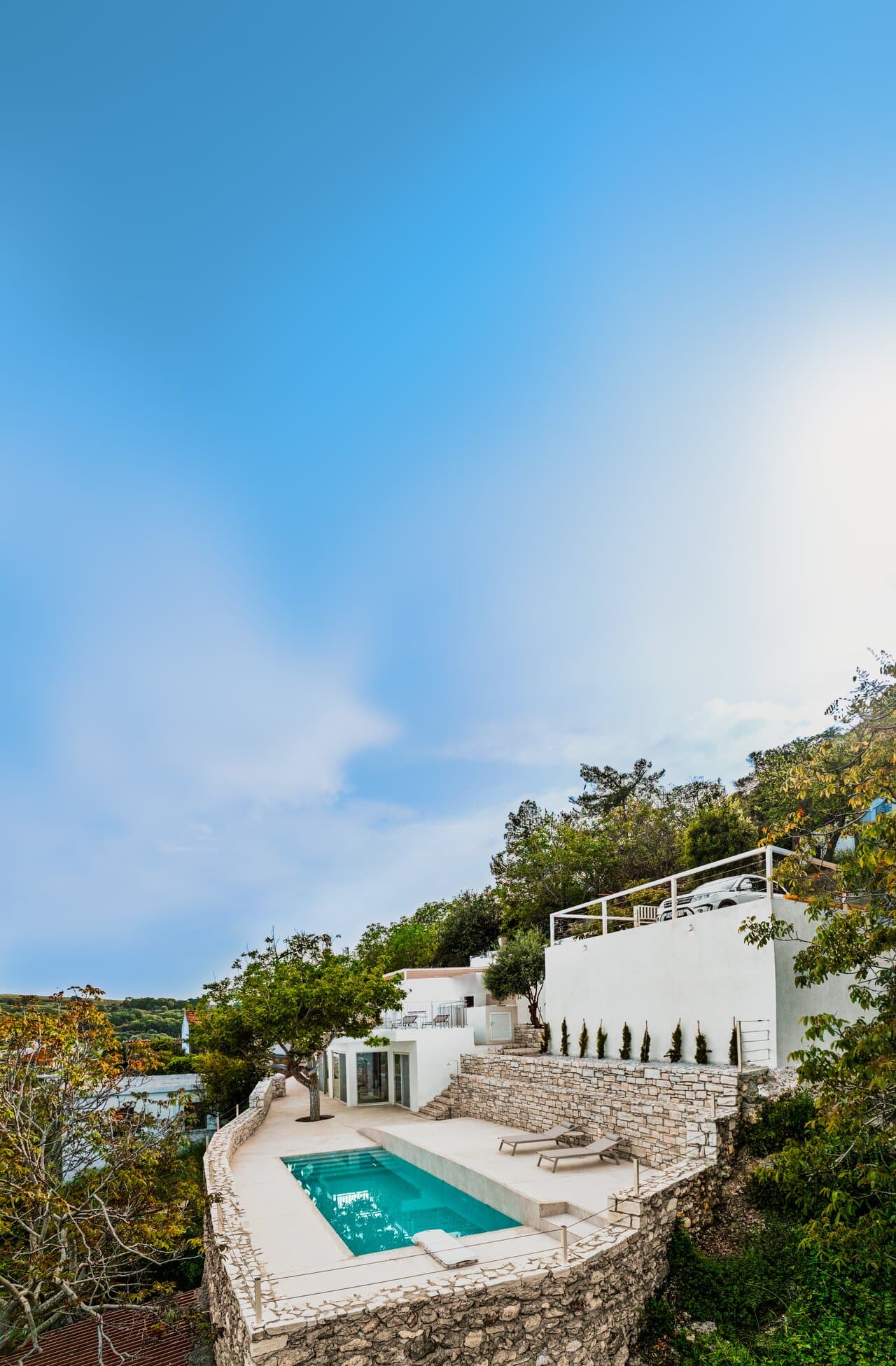 Tall view of Nogal Retreat with the pool, terrace, and white walls beneath a broad blue sky