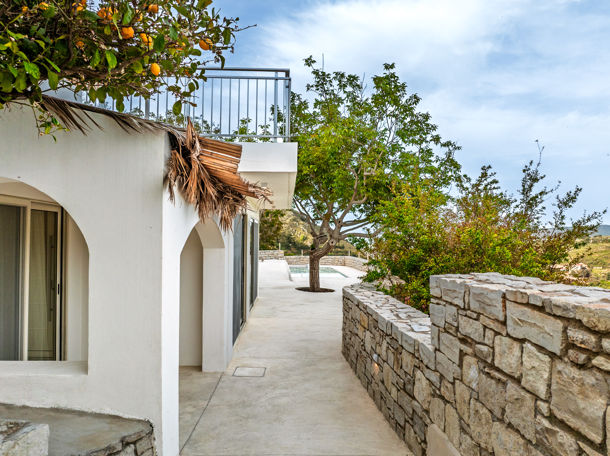 Stone path beside the white villa walls and orange tree